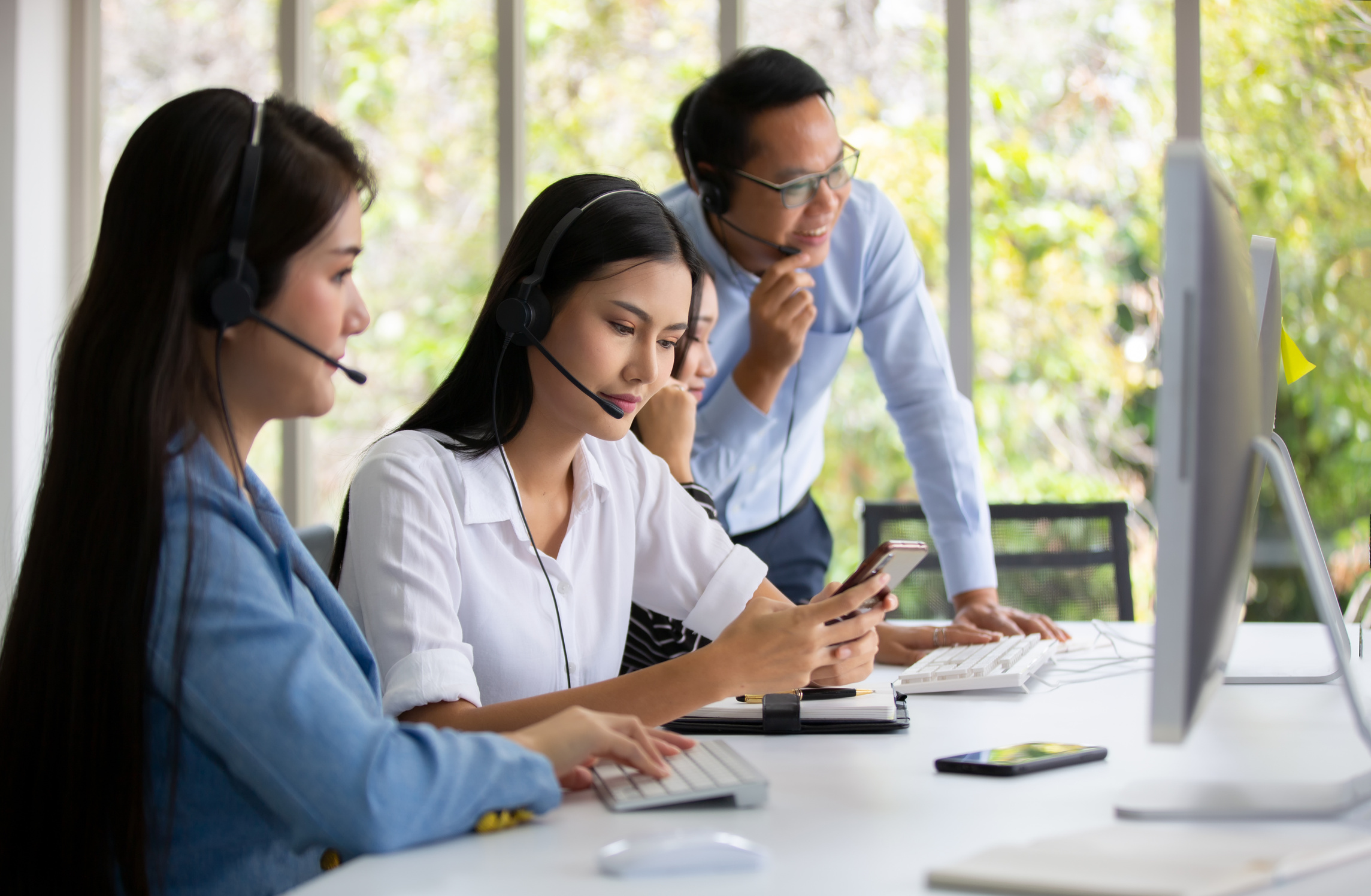 Call Center Agents with Headsets Sitting in the Office